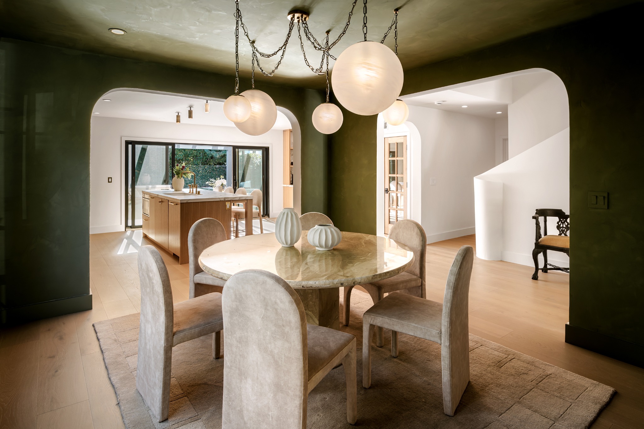 Dining room with sculptural pendant lights and arched openings to the kitchen